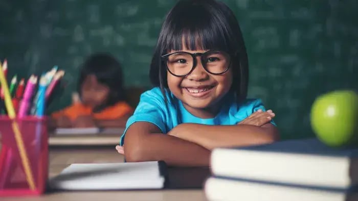 Girl, smiling while keeping her face on books