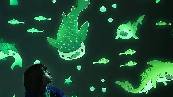 Kid sitting by a wall with glowing stickers