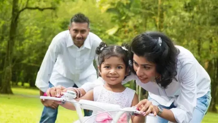 Indian kids cycling in park with parents