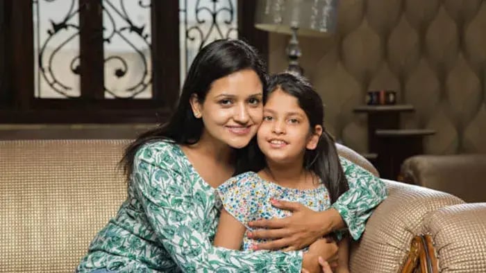 Indian mom and daughter sitting on sofa