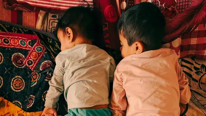 two kids sleeping on a bed