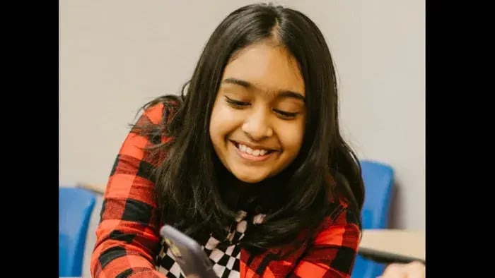Social Media and Students: Understanding Its Advantages and Disadvantages - Girl smiling while using a phone