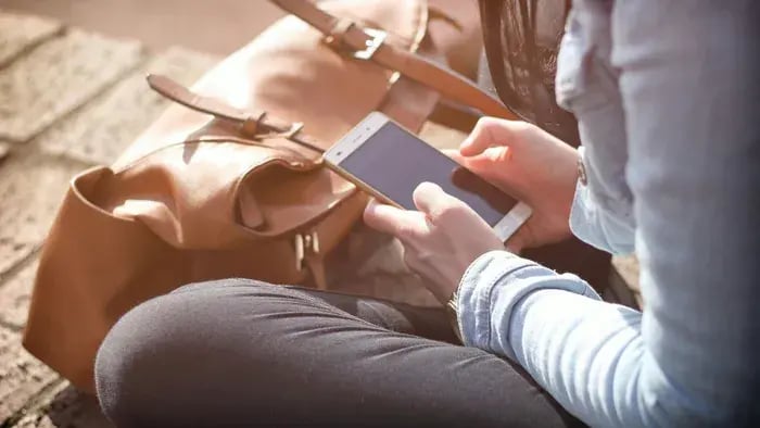 Social Media and Students: Understanding Its Advantages and Disadvantages - Girl using phone with her backpack on the side