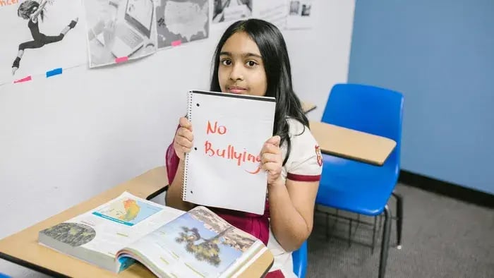 Girl Sitting On A Bench With A No Bullying Poster